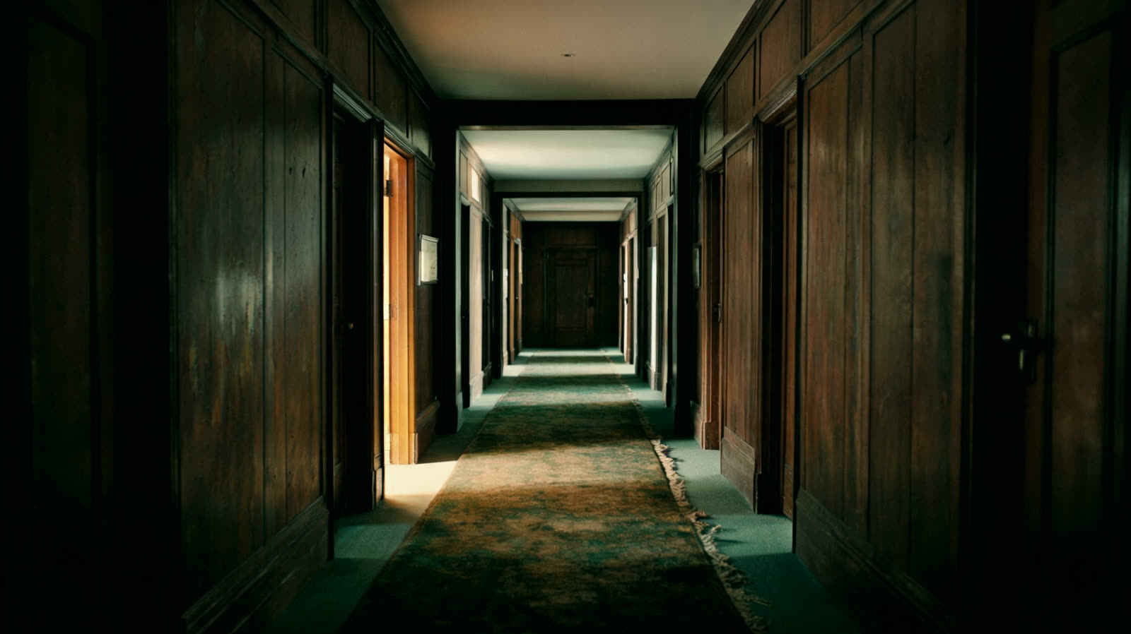 A quiet wood panelled corridor with light from an open doorway
