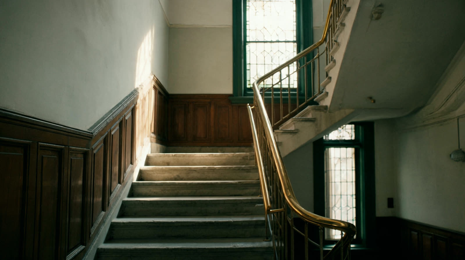 A stone staircase with a brass handrail in an entrance hall